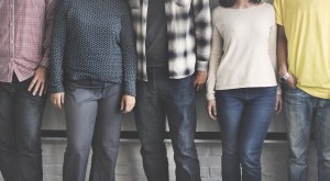 five people stood in front of a white screen. Their heads and feet are cropped out of the image.
